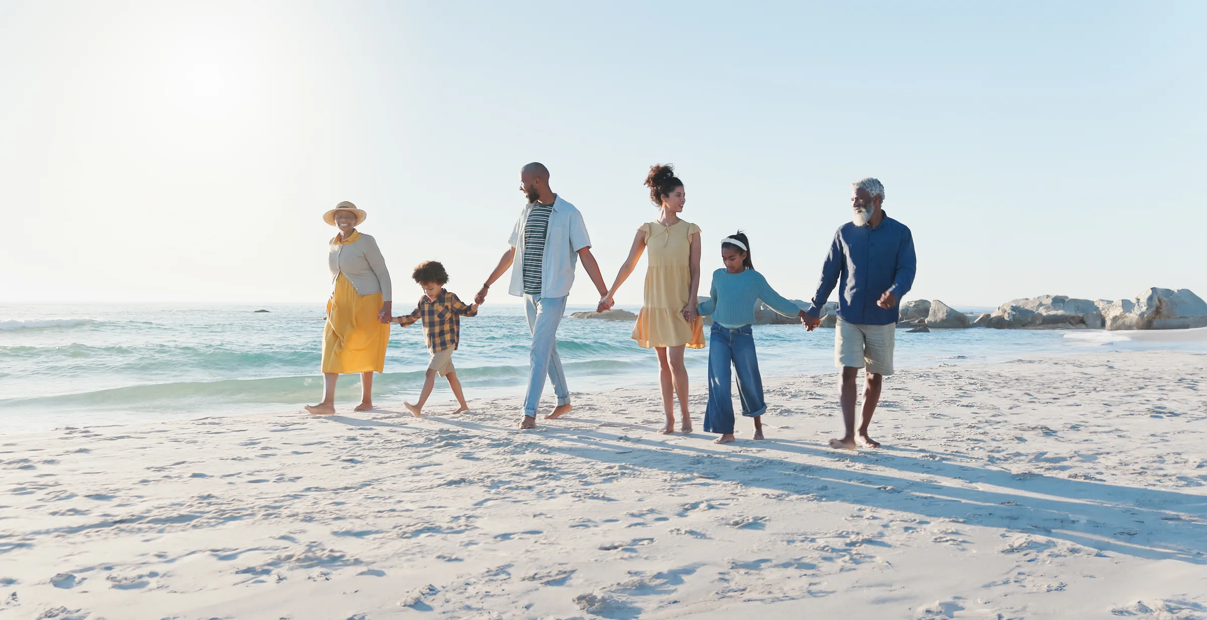 Family walking together along a sunny beach.