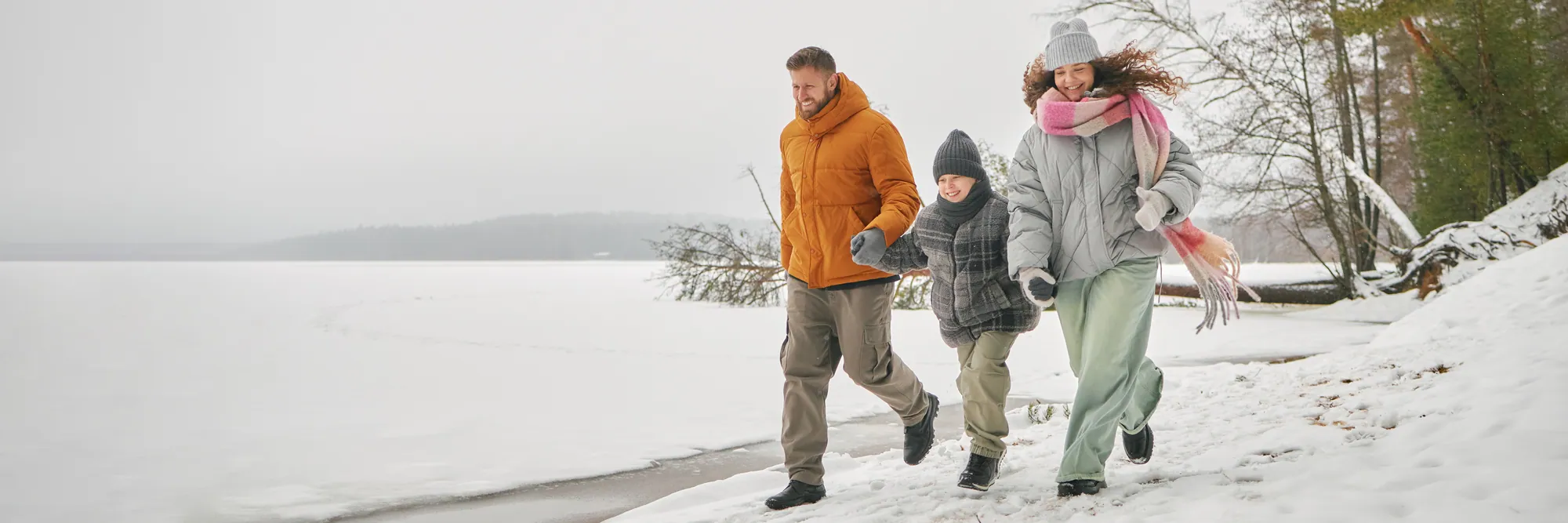 Family walking together beside a frozen lake in winter.